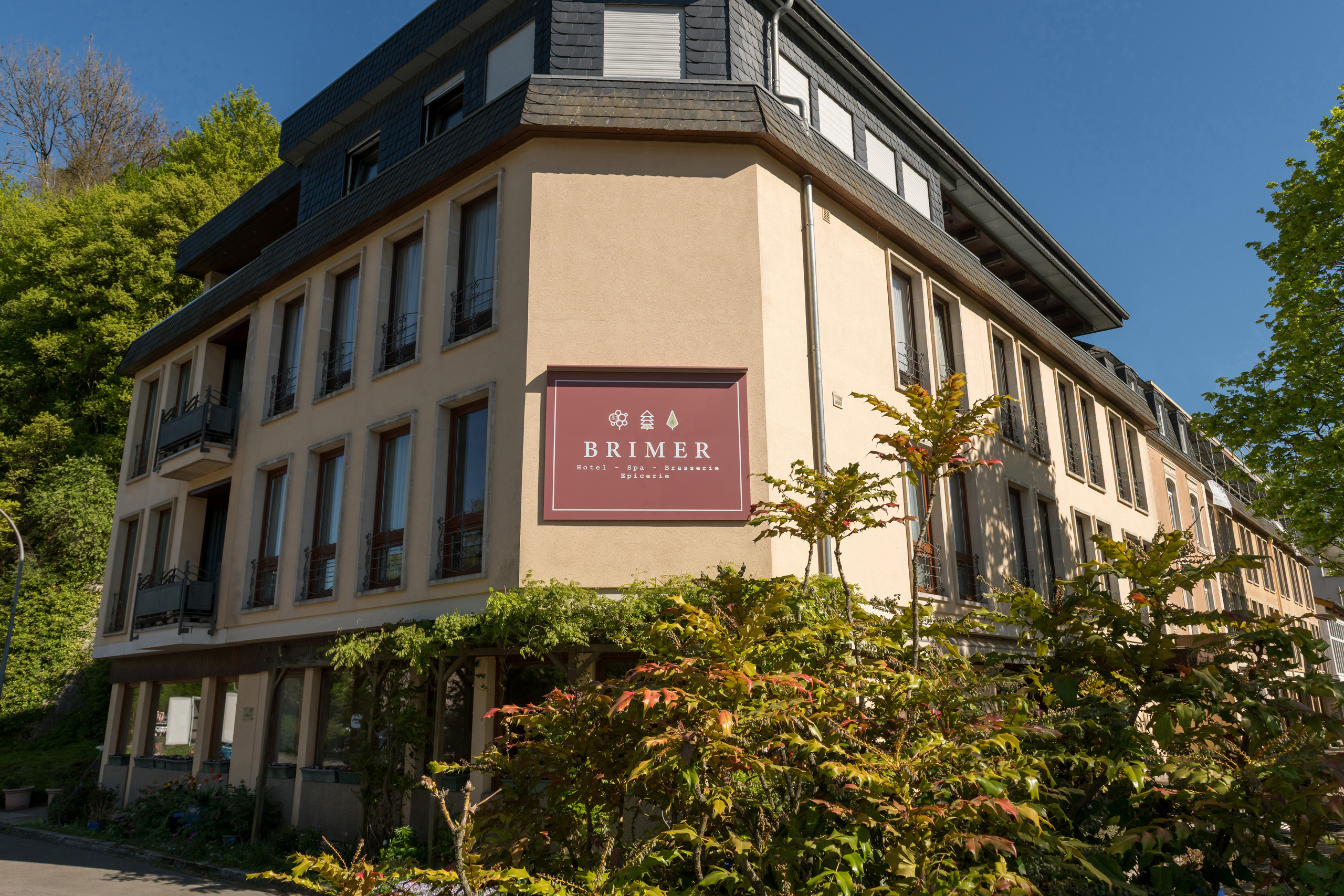 Voorgevel van Hôtel Brimer in Grundhof met het uithangbord, onder een blauwe lucht
